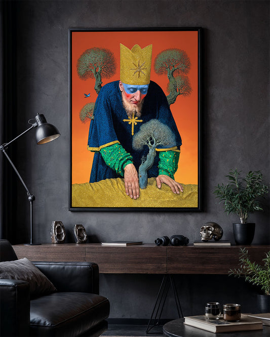 Framed poster of a crowned figure leaning over a small tree, hanging on a dark wall above a wooden desk with lamp, skull and plants.