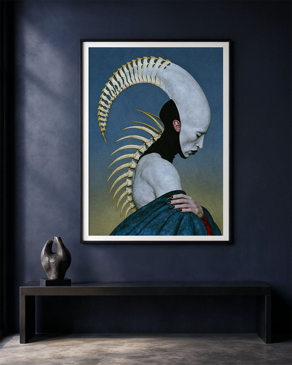 Pleroma surreal anatomical art print displayed in a black frame with a white border on a dark blue wall above a minimalist black bench and small sculptural object.