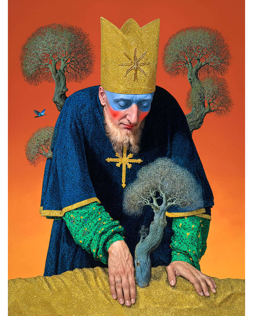 Surreal portrait of a crowned figure with blue and red face paint, wearing a dark robe and gold cross, leaning over a small tree against an orange background.