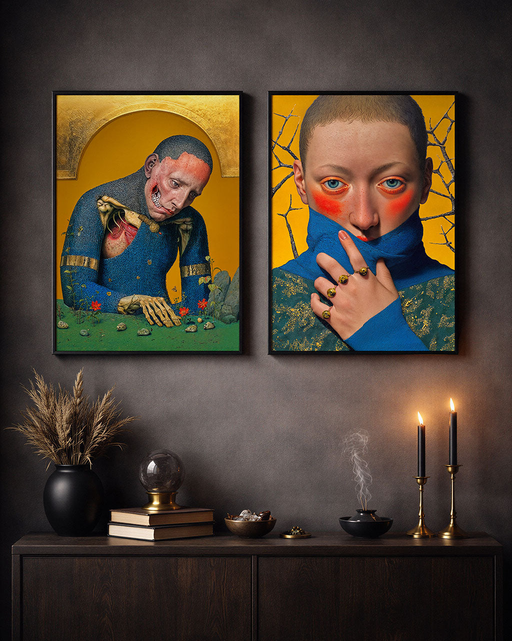 Two framed surreal portrait posters with intricate details displayed above a dark wooden console table with candles, books and decorative objects in a moody interior.
